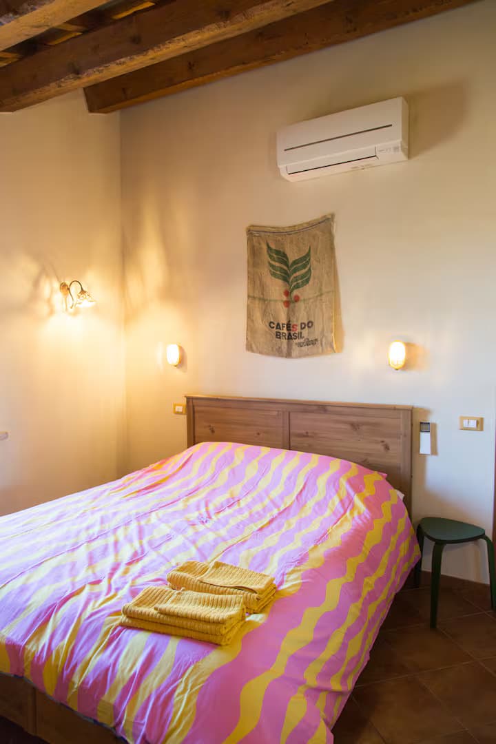 Double bed with colorful bedding, wooden beams and warm lighting