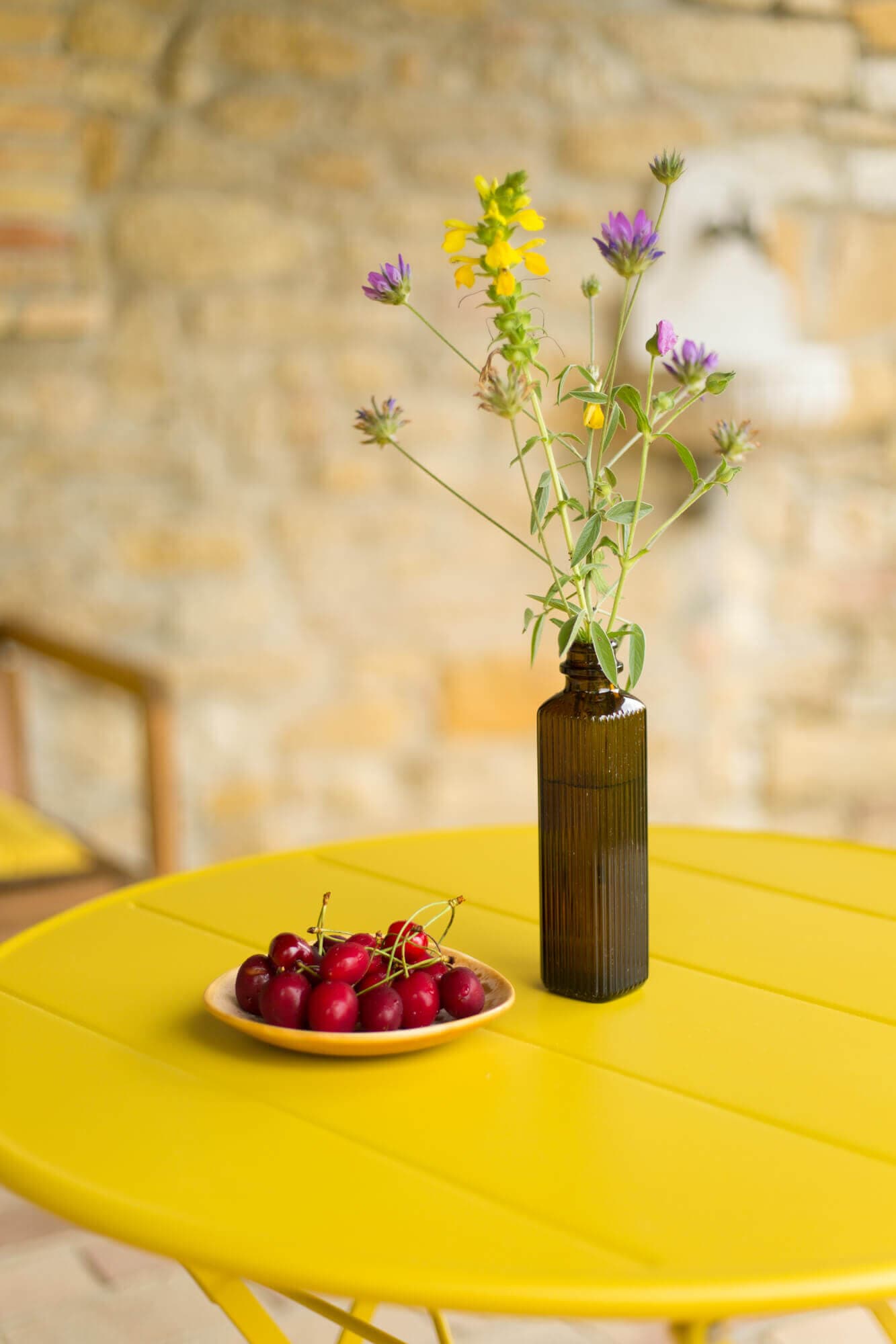 Fresh cherries and wildflowers on a yellow table