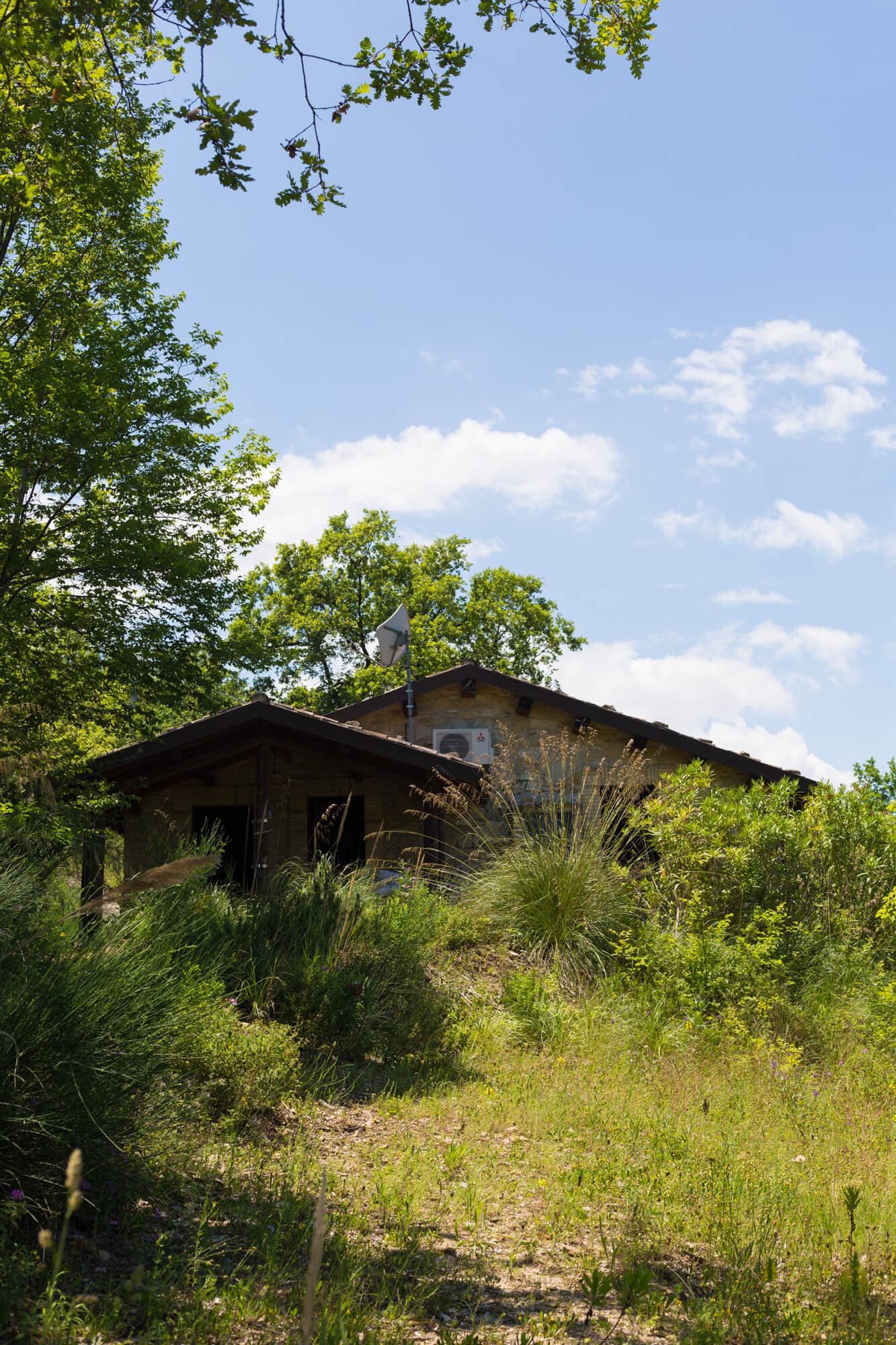 Stone cottage nestled on a green hillside under blue sky