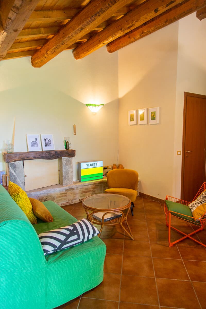 Living room with green sofa, wooden beams and stone fireplace
