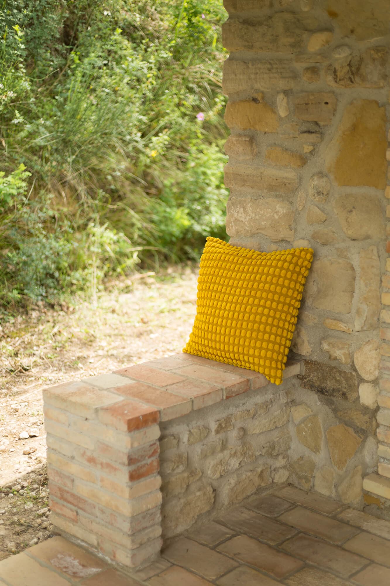 Yellow cushion on stone ledge of the covered patio