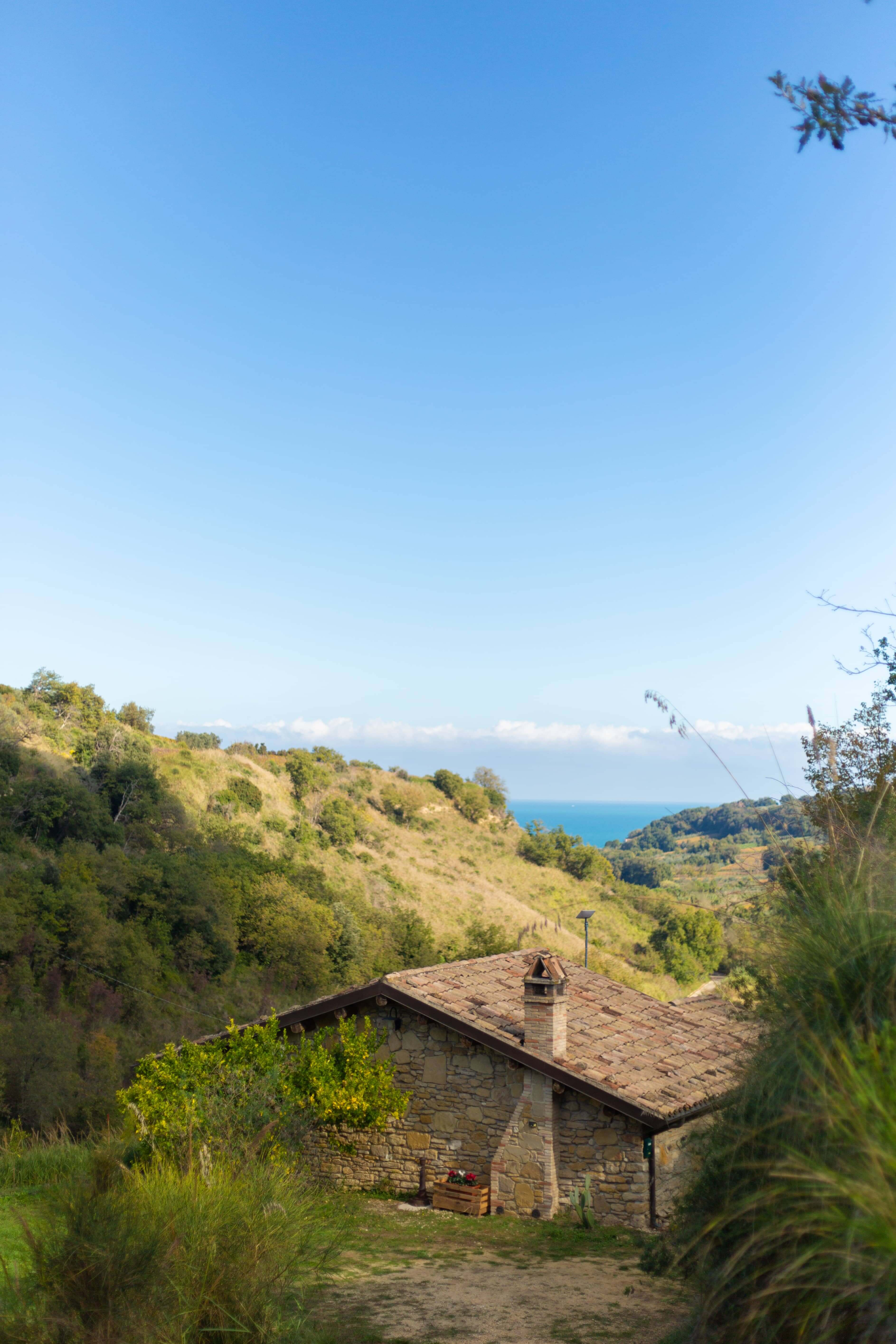 Stone cottage with tile roof surrounded by green hills with sea view in Abruzzo