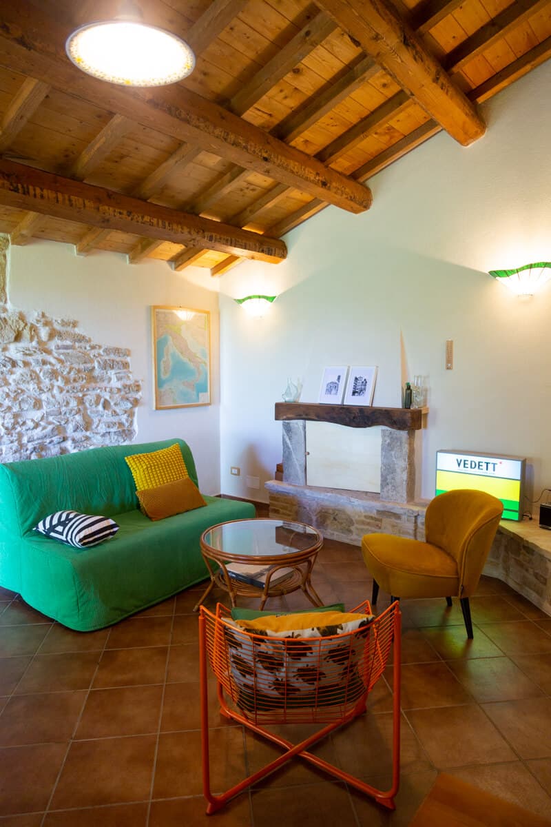 Cozy living room with stone wall, wooden beams, fireplace and colorful furniture